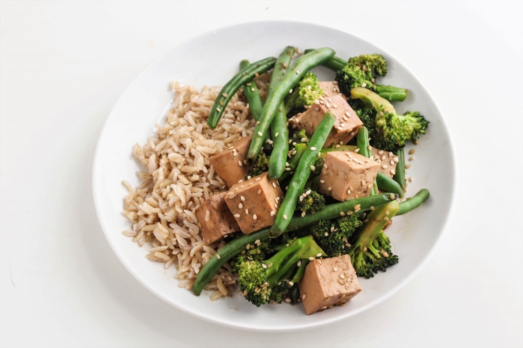 teriyaki tofu stir fry in a white bowl with brown rice