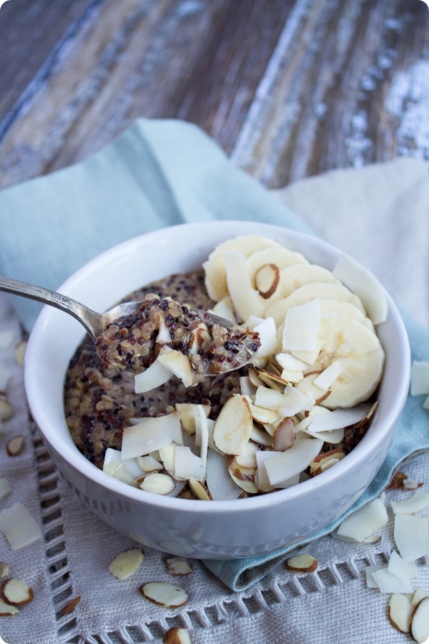 breakfast quinoa in a bowl with coconut flakes, sliced almonds, and banana slices