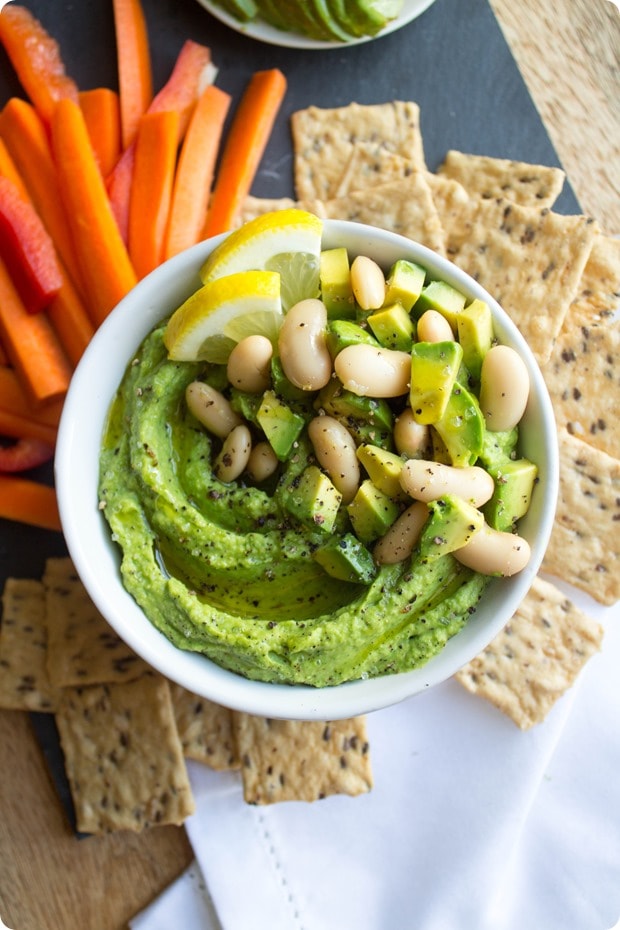avocado hummus 1 lemon avocado white bean hummus in a small white bowl with carrots and crackers beside it