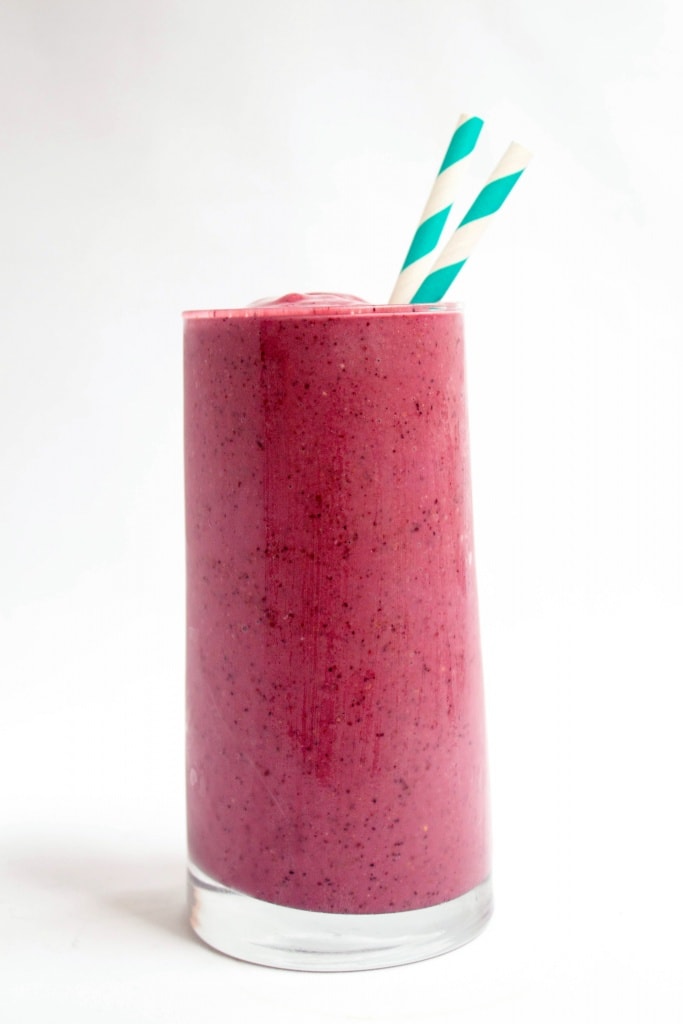 berry yogurt smoothie in a tall glass with striped straws