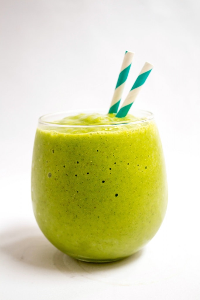 tropical kale fruit smoothie in a short glass with striped straws
