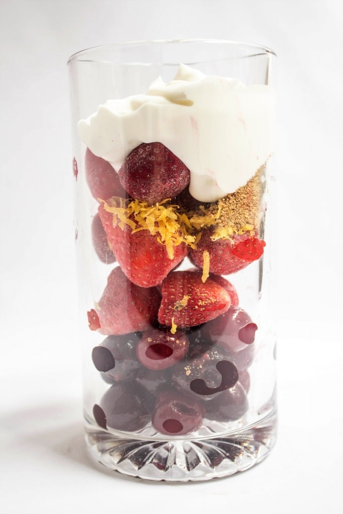 strawberries and cherries in a tall glass with lemon zest and Greek yogurt
