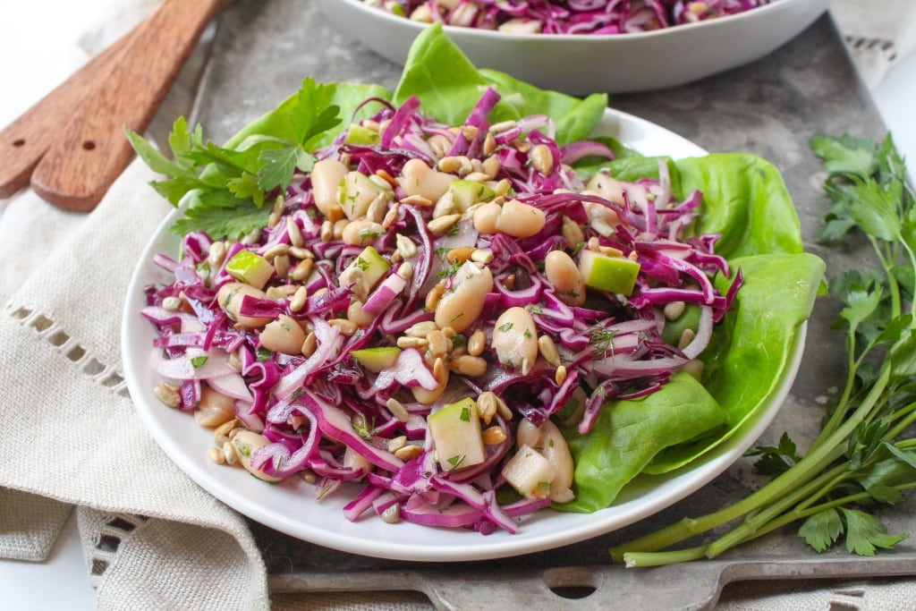 apple cabbage slaw with white beans over a bed of lettuce