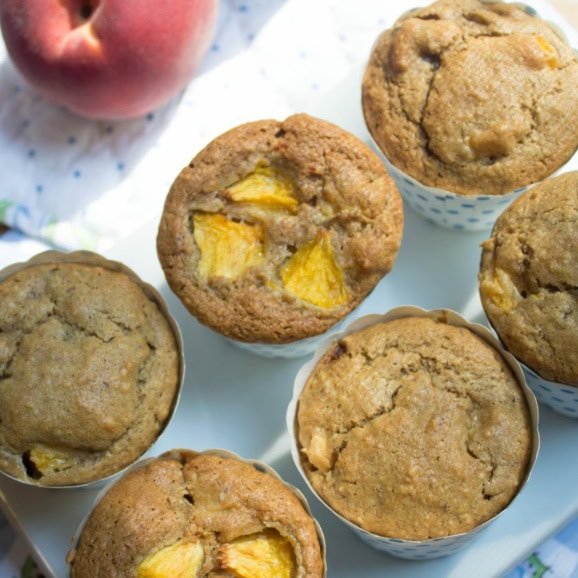 peach muffins next to a fresh peach