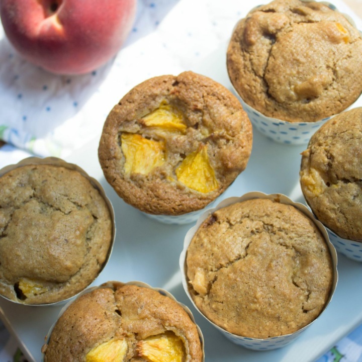 peach muffins next to a fresh peach