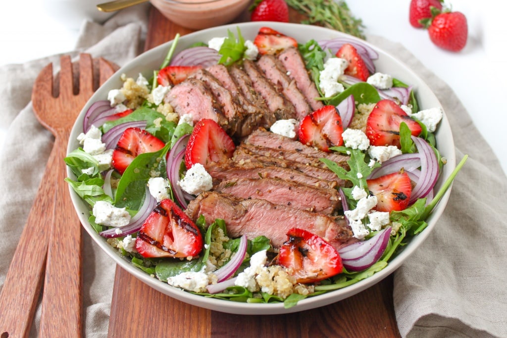 steak and strawberry goat cheese salad with wooden salad spoons
