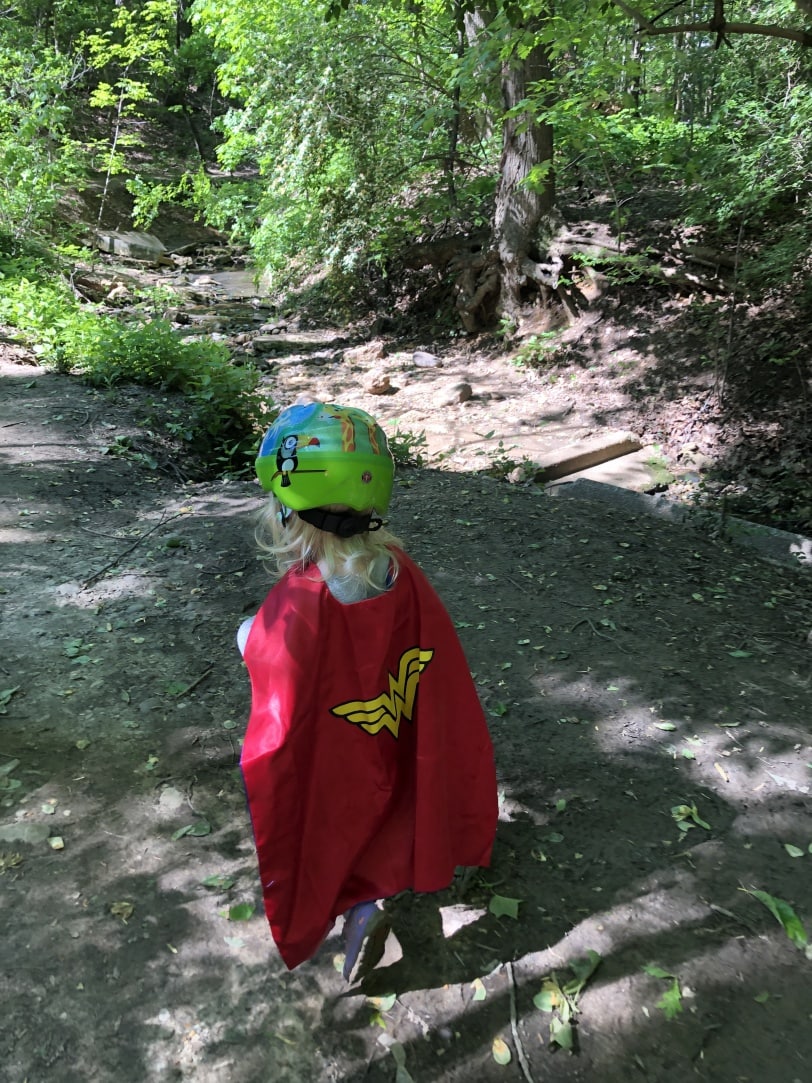 toddler hiking wearing a cape and helmet