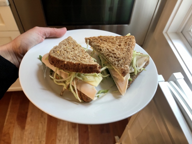 sandwich made with turkey, broccoli slaw, cheese, arugula, and hummus