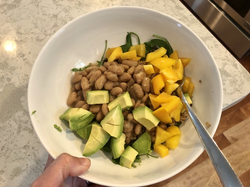 easy lunch bowl with avocado, beans, rice, quinoa, yellow bell peppers, and wilted spinach
