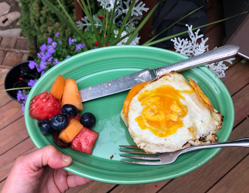egg and cheese on an english muffin with fruit