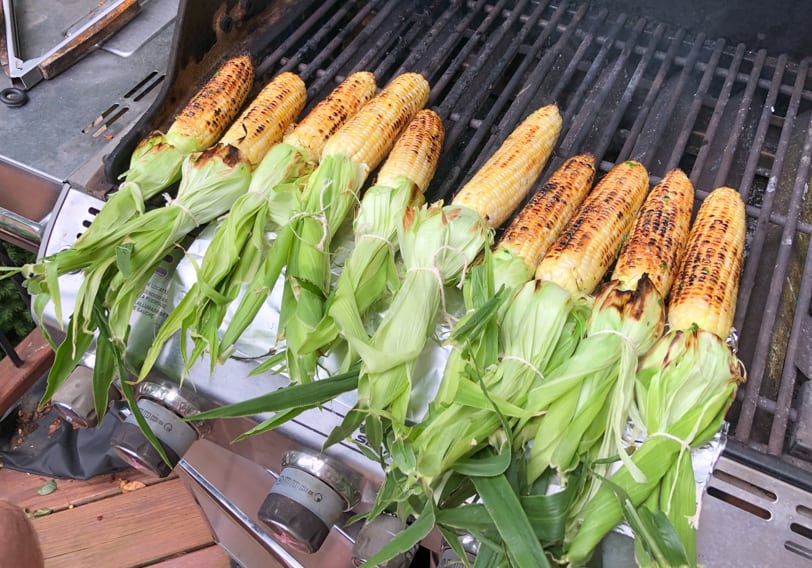 corn on the grill with the husks flipped up