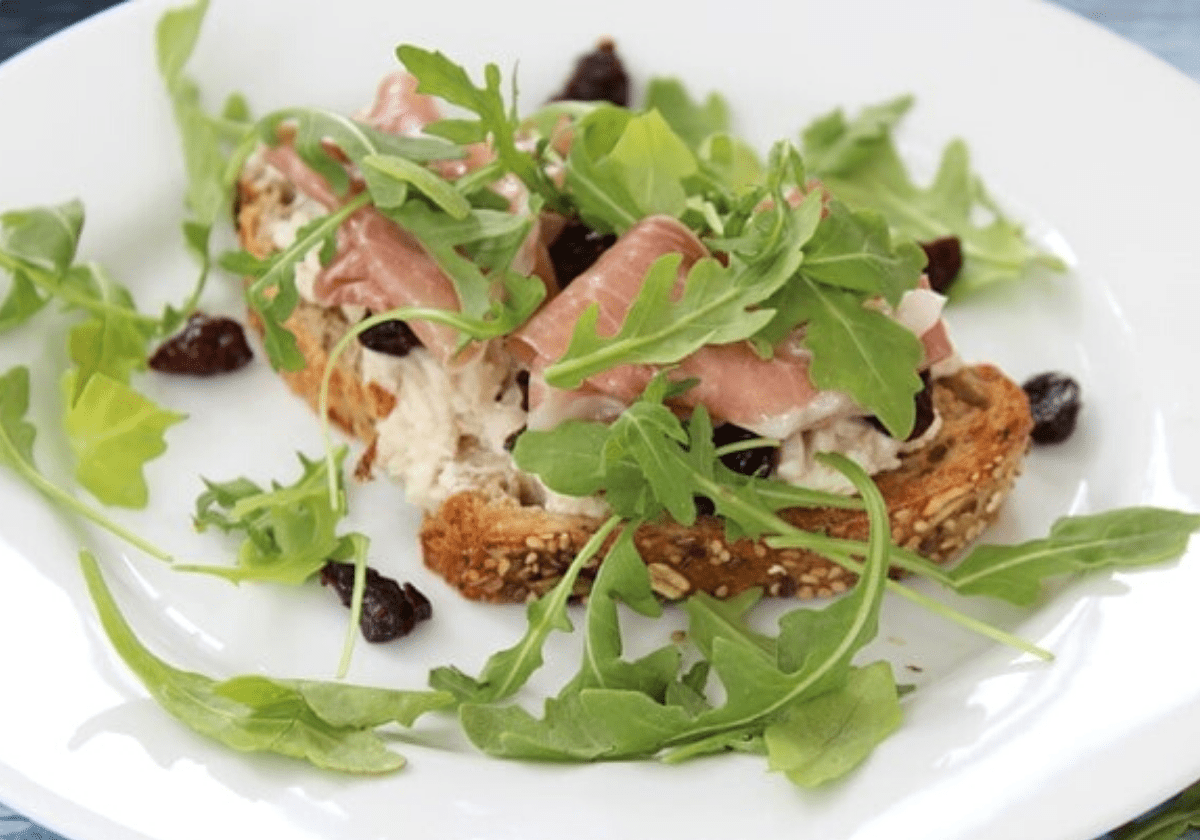 open faced prosciutto sandwich with tart cherries and arugula