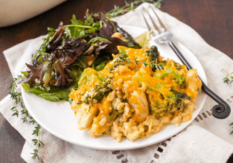 chicken broccoli rice casserole with a side salad on a white plate with a fork