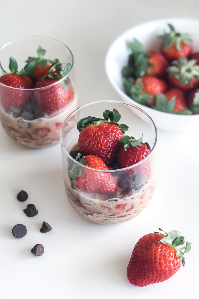 chocolate strawberry overnight oats in jars with a bowl of strawberries in the background