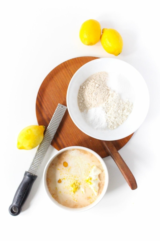 lemons next to a bowl with flour and sugar and a bowl with eggs, milk, and ricotta cheese