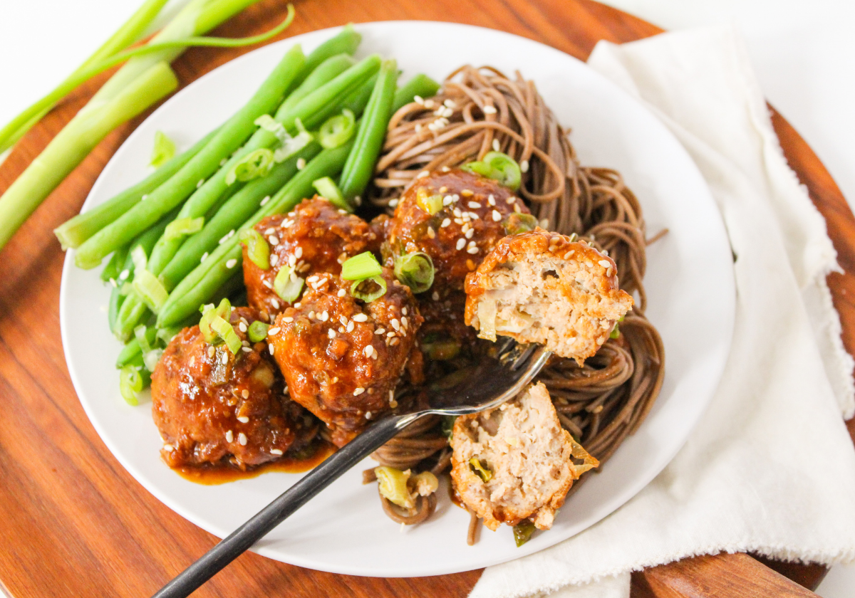 honey sriracha meatballs on a plate with green beans