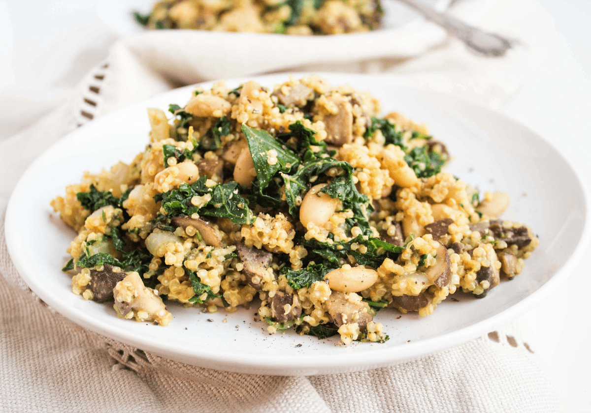 cheesy mushroom quinoa with spinach on a white plate