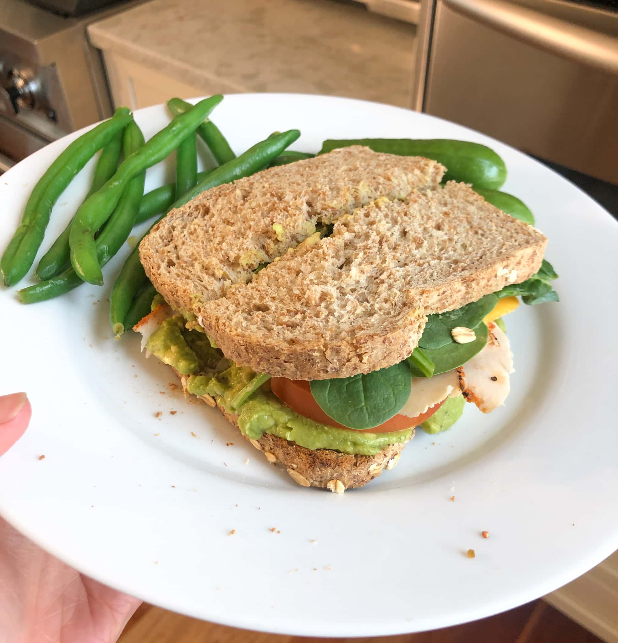 sandwich with guacamole, cheddar cheese, turkey, tomato, and spinach