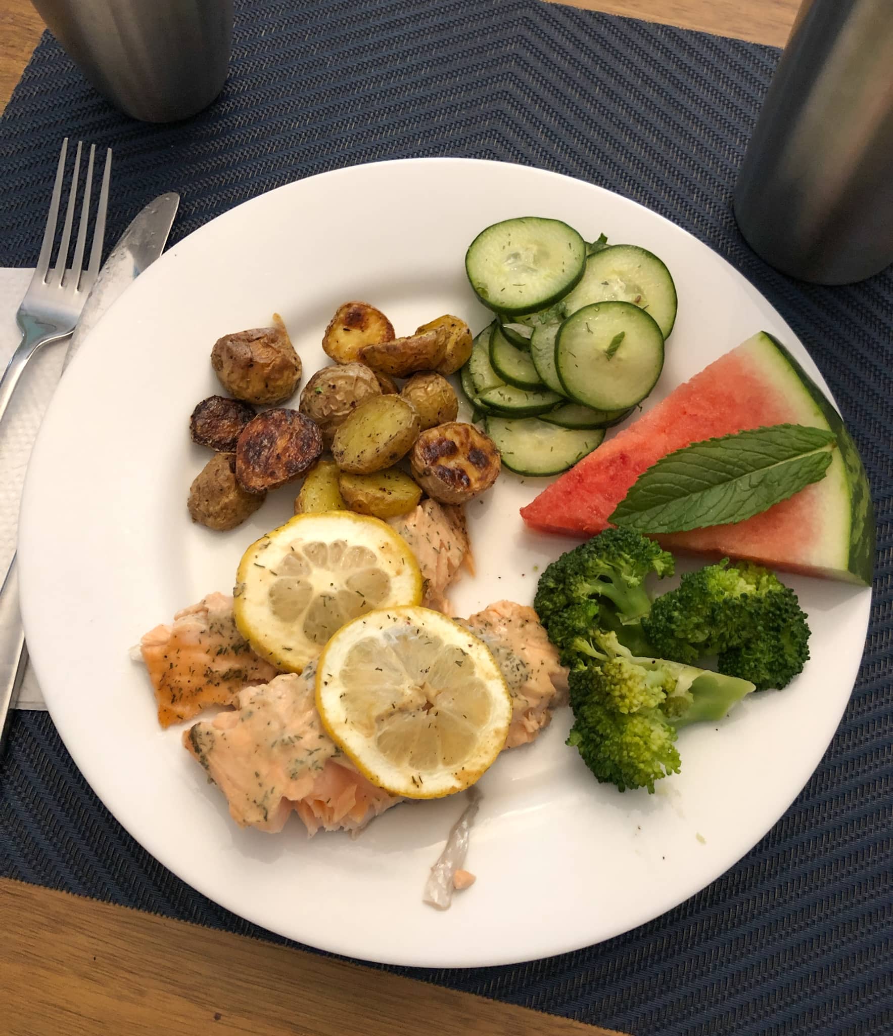salmon with broccoli, roasted potatoes, cucumber salad, and watermelon.