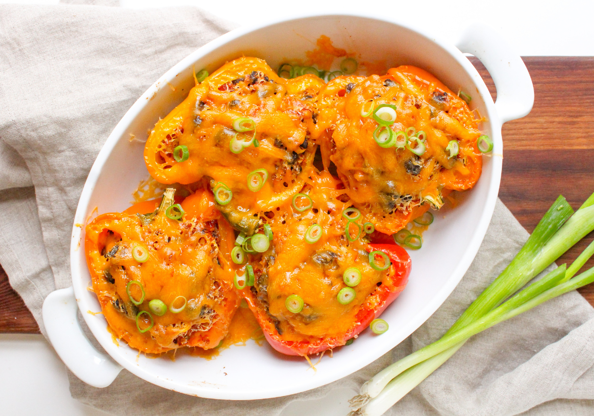 Mexican stuffed bell peppers topped with cheddar cheese in a white ceramic baking dish