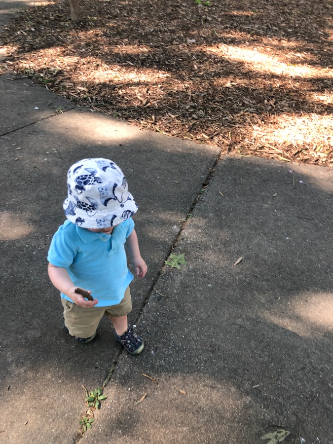 toddler walking with a hat on.