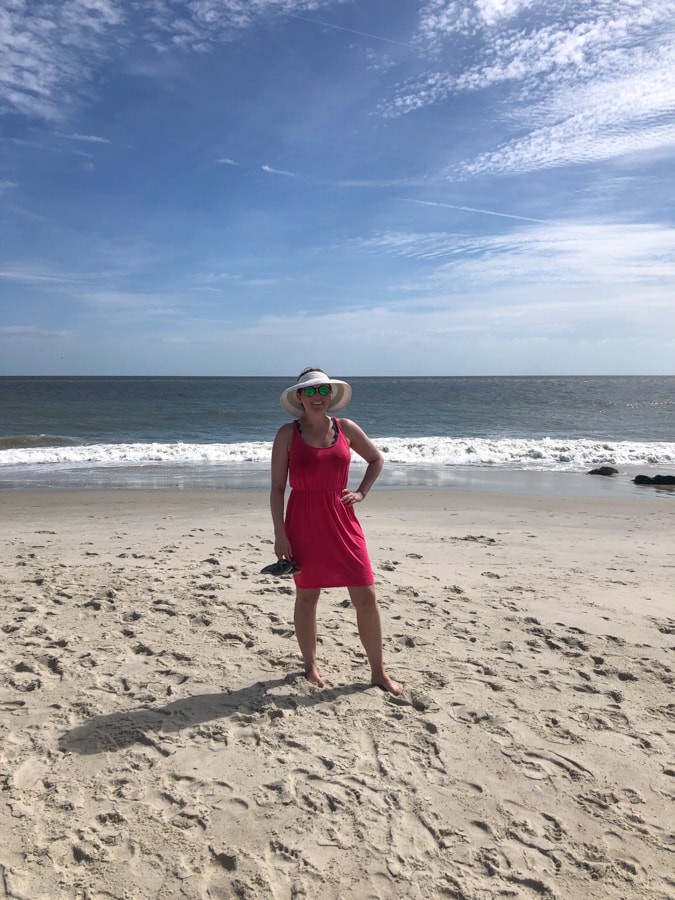 anne mauney standing on the beach in a pink dress
