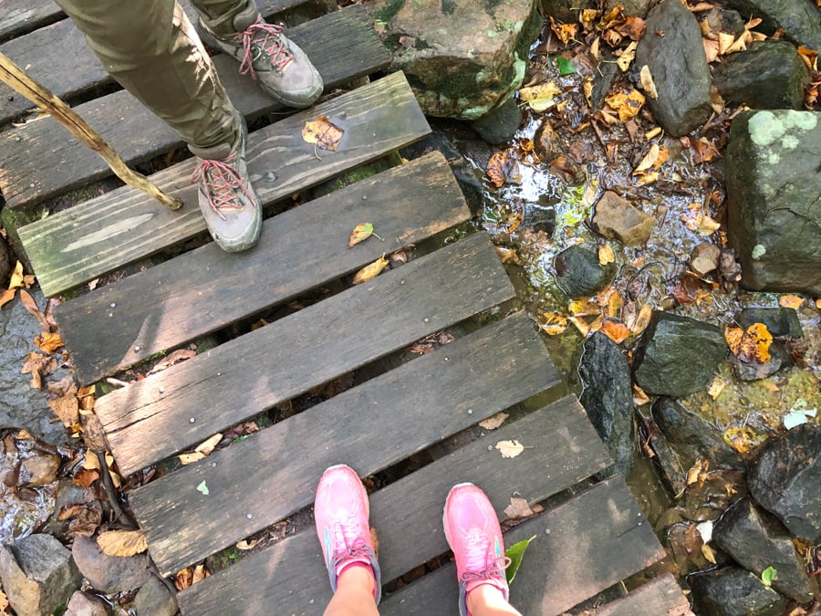 feet on a bridge in the woods