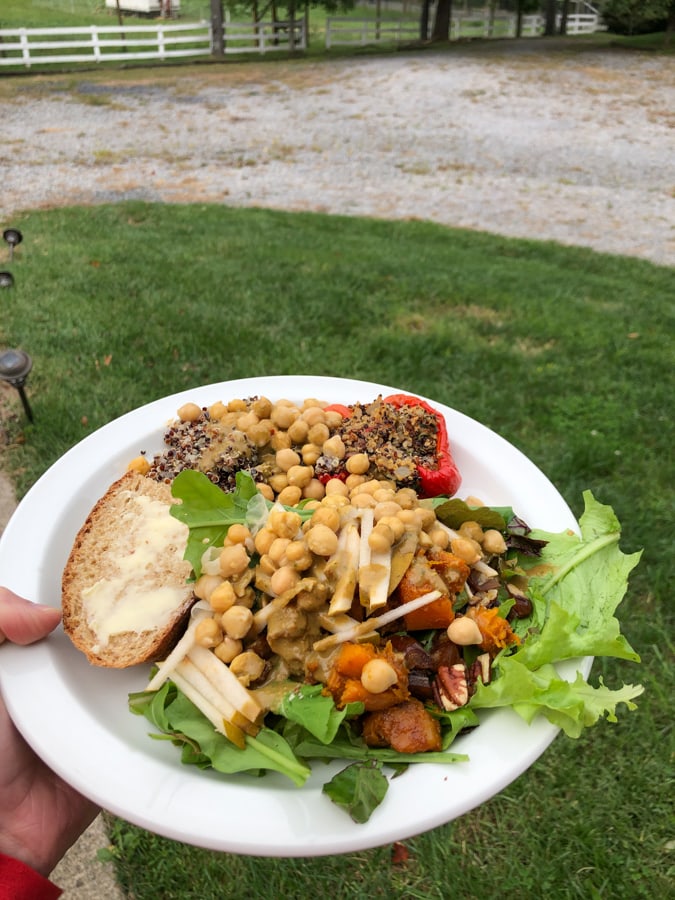 white plate with a large chickpea salad, bread, and a stuffed red pepper.