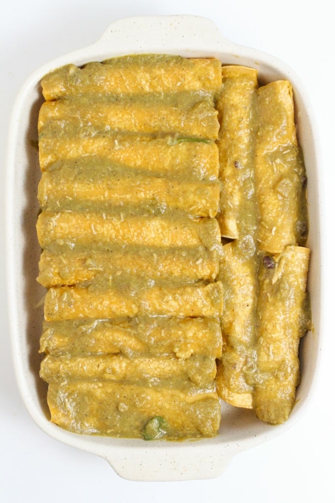 rolled tortillas in a baking dish with salsa verde on top