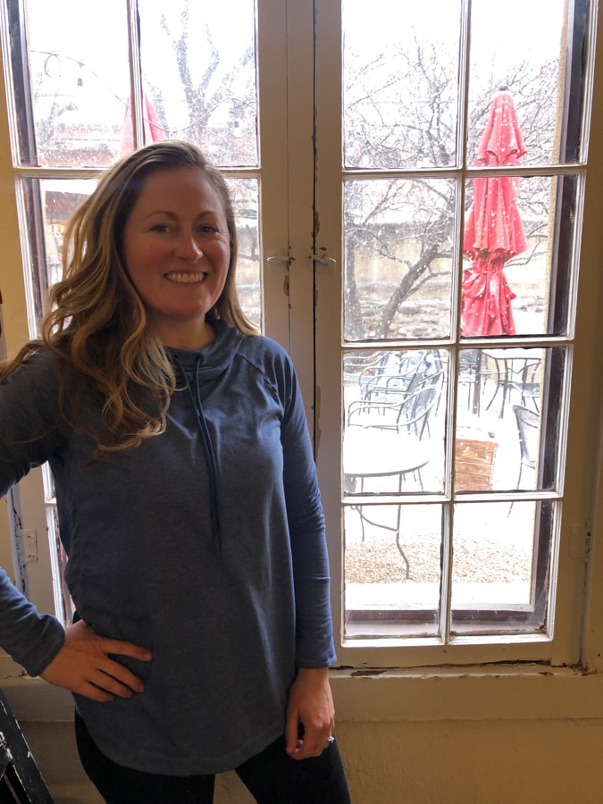 anne mauney standing at a window with snow outside