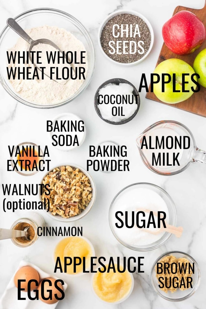 apples, white whole wheat flour, chia seeds, sugar, applesauce, eggs, brown sugar, and more baking ingredients on a marble surface