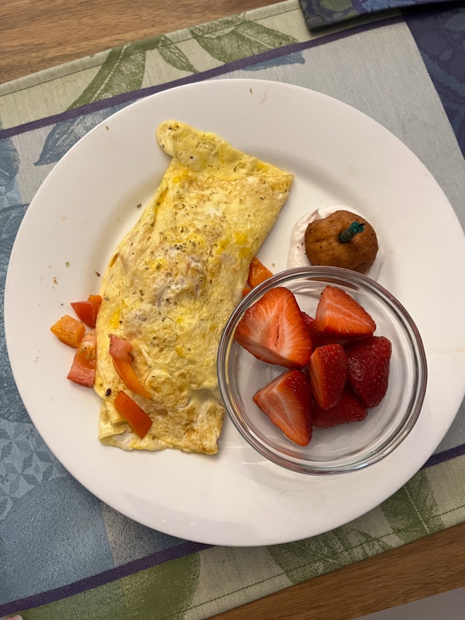 omelette, strawberries, and a donut with a candle in it