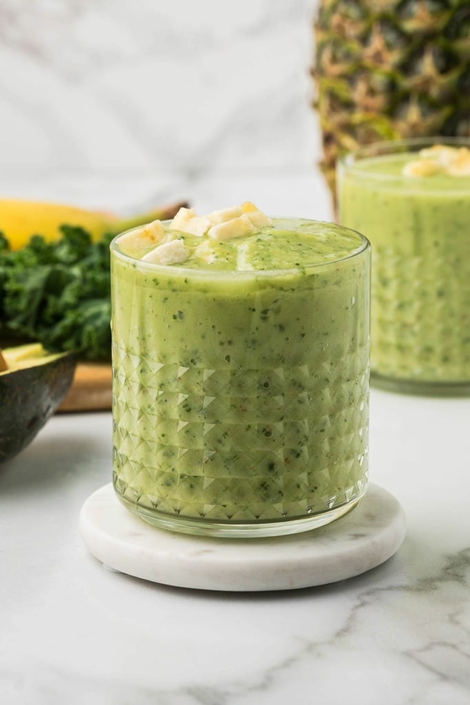 green kale smoothie with banana and pineapple in a short glass