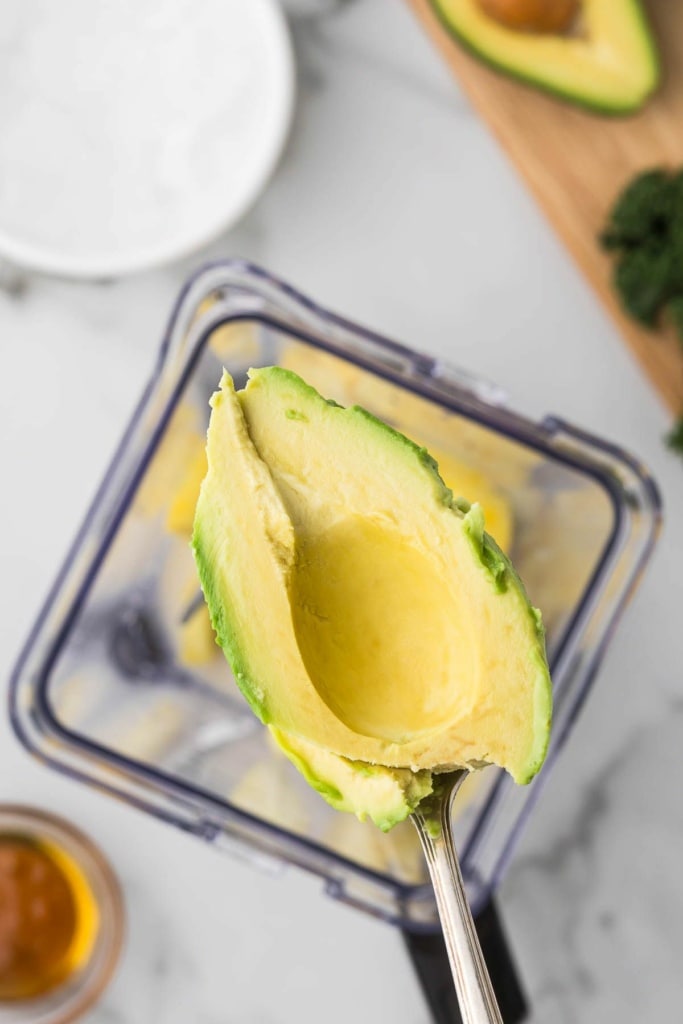 avocado being spooned into a blender