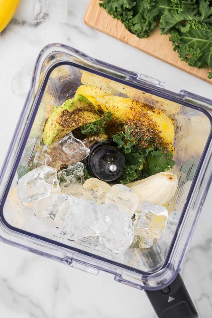 ice cubes, kale, pineapple, and banana in a blender
