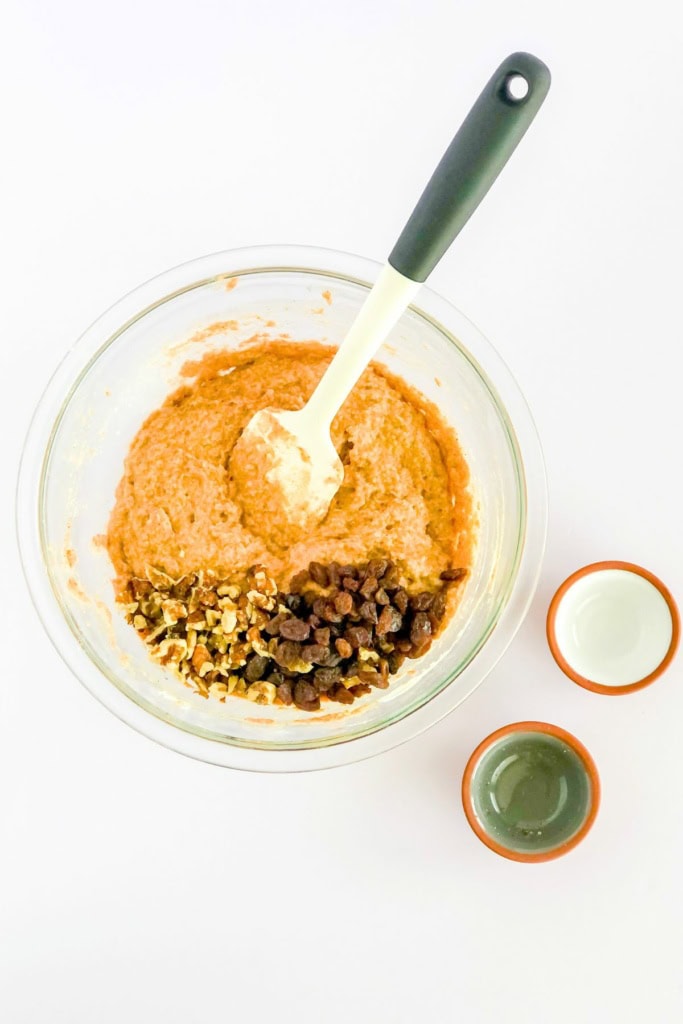 carrot cake muffin batter with walnuts and raisins in a glass bowl